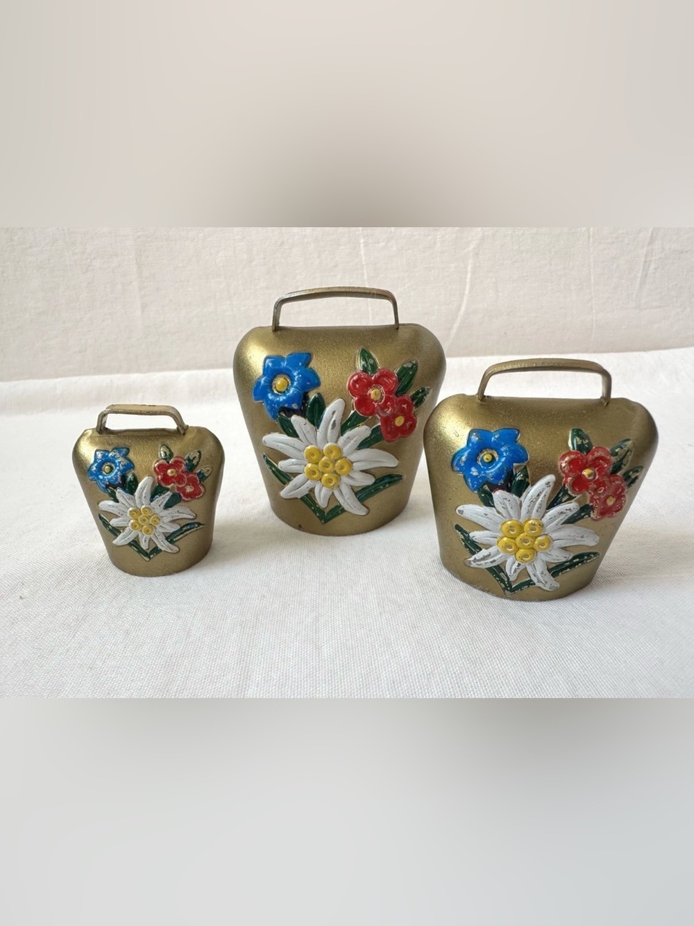 This set of 3 vintage Swiss cow bells features a charming hand-painted design of